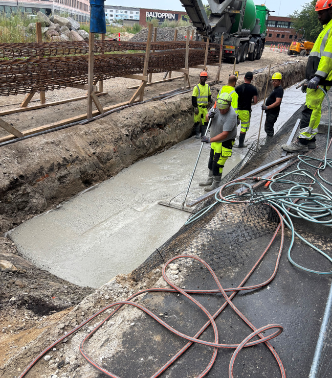 Mennesker i arbejdstøj som støber beton 